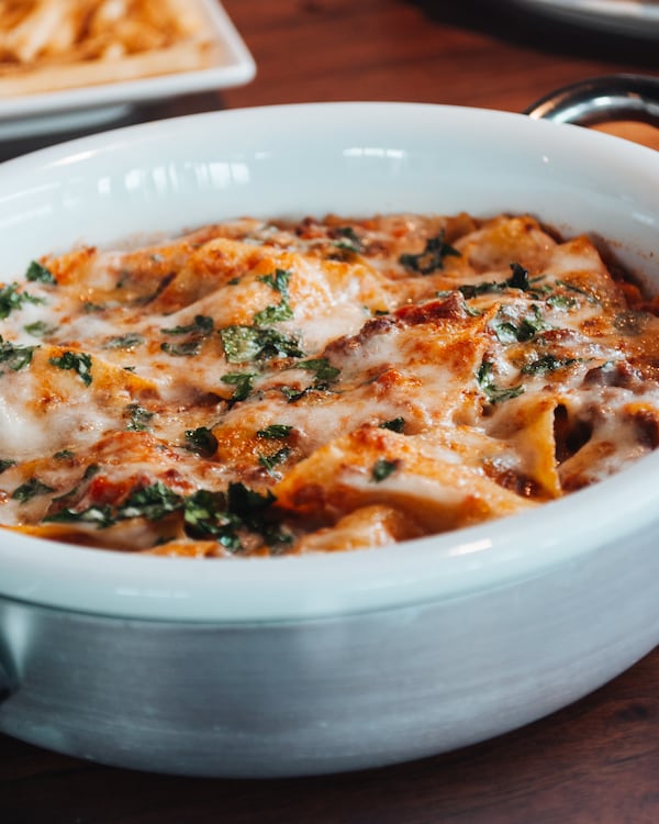a large bowl of pasta with red sauce and cheese melted on top in a restaurant