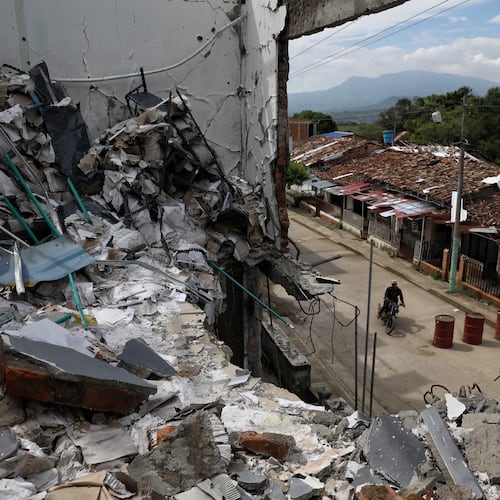A man rides his motorcycle past the ruins of homes destroyed five months earlier in an attack by dissidents of the former Revolutionary Armed Forces of Colombia, or FARC, in Buenos Aires, Cauca, Colombia, Wednesday, May 20, 2026.(AP Photo/Santiago Saldarriaga)