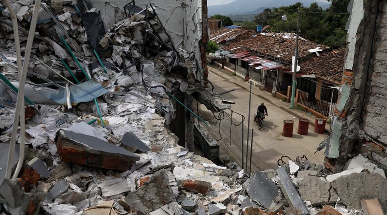 A man rides his motorcycle past the ruins of homes destroyed five months earlier in an attack by dissidents of the former Revolutionary Armed Forces of Colombia, or FARC, in Buenos Aires, Cauca, Colombia, Wednesday, May 20, 2026.(AP Photo/Santiago Saldarriaga)