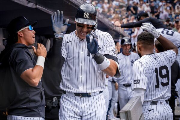 New York Yankees' Aaron Judge (99) celebrates in the dugout after hitting a grand slam in the third inning of a baseball game against the Milwaukee Brewers, Saturday, March 29, 2025, in New York. (AP Photo/Angelina Katsanis)