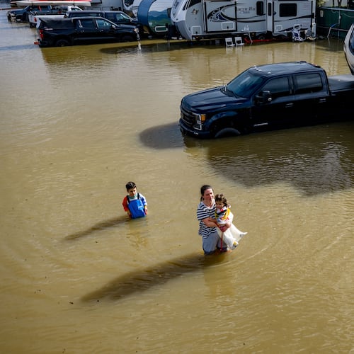 FILE - People wade through a recreational vehicle park flooded by a king tide on Jan. 3, 2026, near Corte Madera in Marin County, Calif. (AP Photo/Ethan Swope, File)