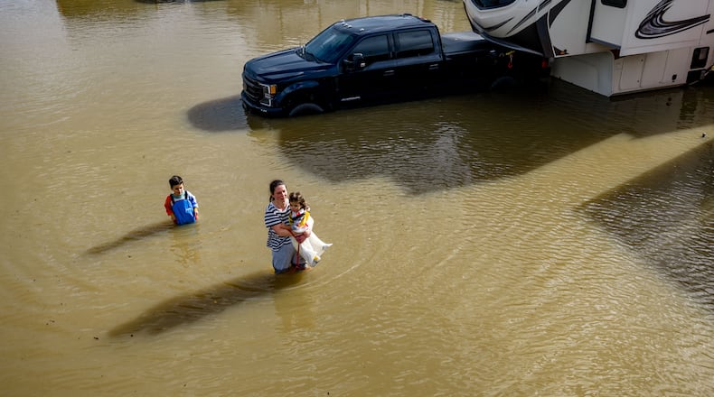 FILE - People wade through a recreational vehicle park flooded by a king tide on Jan. 3, 2026, near Corte Madera in Marin County, Calif. (AP Photo/Ethan Swope, File)