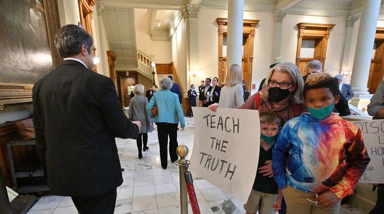 Educators and their children hold signs to protest outside the meeting room of the House Appropriations Committee at the Georgia State Capitol on Tuesday, March 15, 2022. This session, education was a wedge issue in the Legislature. (Hyosub Shin / Hyosub.Shin@ajc.com)
