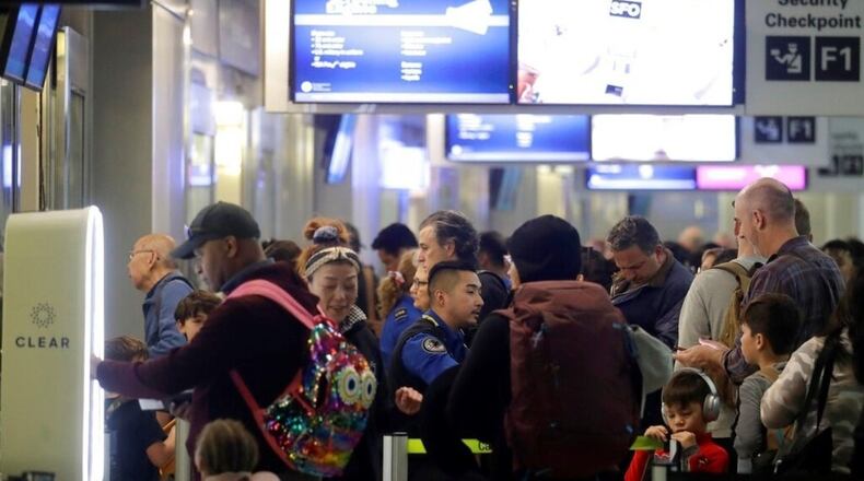 Passengers wait to pass through security gates at San Francisco International Airport, Tuesday, Nov. 26, 2019. Northern California residents are bracing for a 'bomb cyclone.'