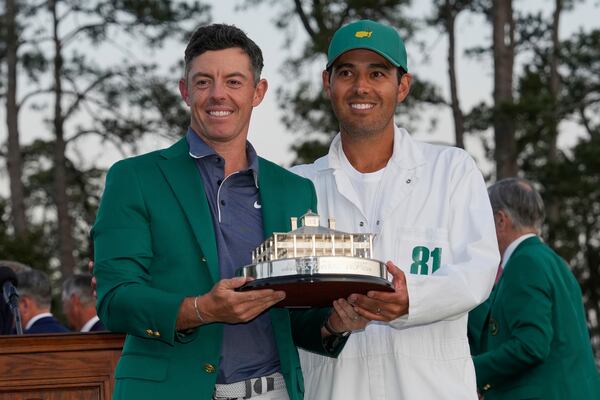 Rory McIlroy, of Northern Ireland, holds the trophy with caddie Harry Diamond after winning the Masters golf tournament, Sunday, April 13, 2025, in Augusta, Ga. (AP Photo/David J. Phillip)