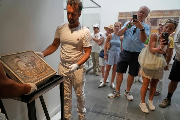 Restorers set on display a Roman mosaic depicting a pair of lovers, which was repatriated from Germany, in Pompeii archaeological park, Italy, Tuesday, July 15, 2025. (AP Photo/Gregorio Borgia)