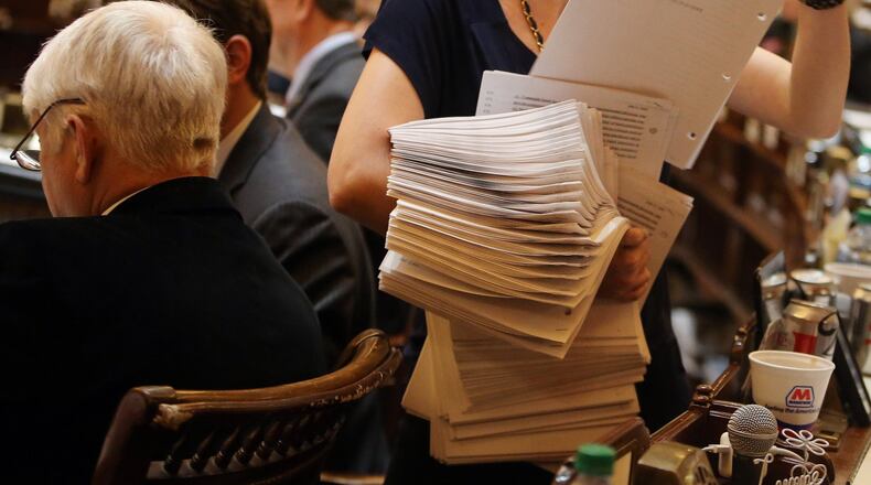 Jamie Momeyer, with the House Clerk’s Office, has her hands full while distributing copies of an amendment in the House chamber Tuesday evening March 18, 2014, the next to last day of the regular Legislative session. BEN GRAY / BGRAY@AJC.COM