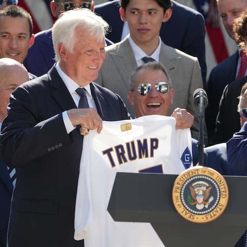 President Donald Trump puts a championship ring into his pocket as owner Mark Walter presents him with a jersey during an event to honor the 2025 World Series champions Los Angeles Dodgers in the Rose Garden of the White House, Thursday, July 23, 2026, in Washington. (AP Photo/Alex Brandon)