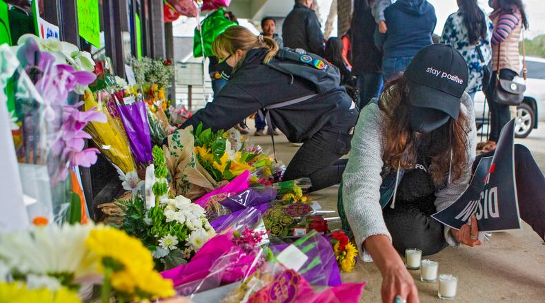 FILE: Two community members set up candles during a candlelight vigil on Thursday, March 18, 2021, in Acworth, Georgia, to honor the lives of Delaina Ashley Yaun, Paul Andre Michels, Xiaojie Tan and Daoyou Feng, who were shot and killed in spas around Acworth, Georgia, and others who were killed in similar shootings in Atlanta, on Tuesday, March 16, 2021. Six of the eight total victims were Asian women. CHRISTINA MATACOTTA FOR THE ATLANTA JOURNAL-CONSTITUTION.