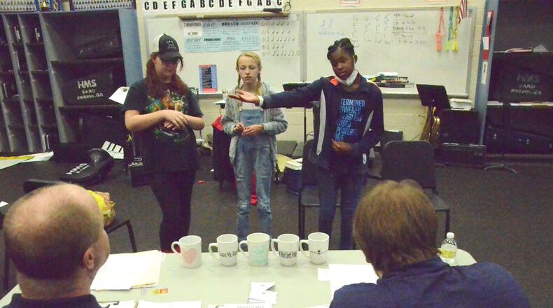 Students Ava James, Kali Taylor and Sanaai Watson pitch their product — Kaz Kups (on table) to “Sharks” Ryan Rigsby and Tyler Allen.