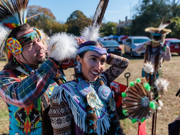 Violet Lauren of Atlanta, a member of the Chickasaw and Cherokee nations, gets help adjusting her wardrobe before dancing at the inaugural First Voices Festival and powwow in Little Five Points in Atlanta on Saturday, Nov. 19, 2022. This year's powwoww was Saturday and runs through Sunday. (Arvin Temkar/AJC 2022) 