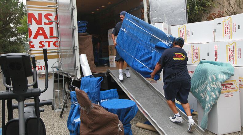 Workers move a piece of furniture into a truck while moving a family.