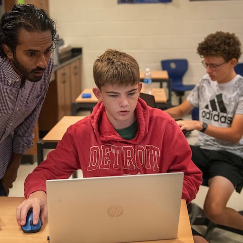From left, Raghu Arghal teaches students Nathan Wright and Graham Long about the ethics of artificial intelligence as they complete an assignment for an AI summer class at Novi High School. Arghal and fellow teacher Adithya Sairamachandran are leading AI Scholars, an in-person boot camp that exposes high school students to fundamental AI concepts and guides them to build a project with social impact. (Neo Hopkins/The Detroit News)