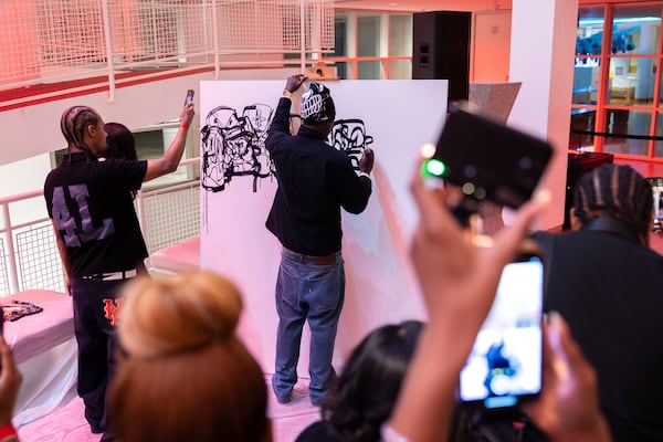 British-Nigerian artist Slawn creates on a canvas at the High Museum in Atlanta on Friday. Slawn designed the cover for 21 Savage’s new album, "What Happened to the Streets?" (Arvin Temkar/AJC)