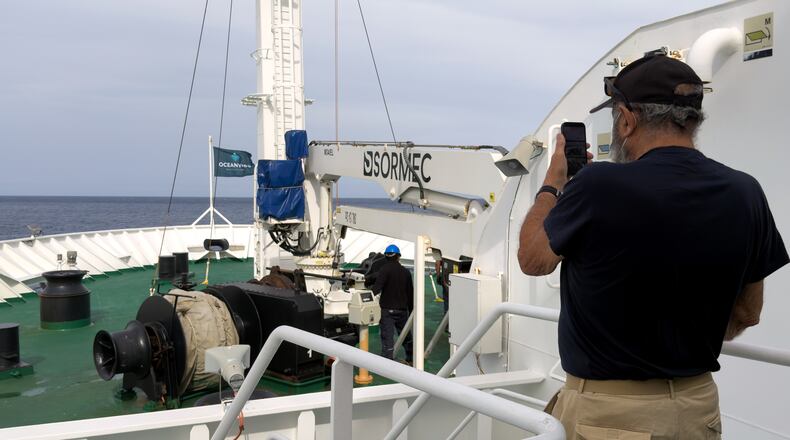 A passenger on the the hantavirus-stricken cruise ship, MV Hondius, takes a photo of the ship's weighing anchor in Praia, during the voyage to Spain's port of Tenerife, May 6, 2026. (AP Photo)