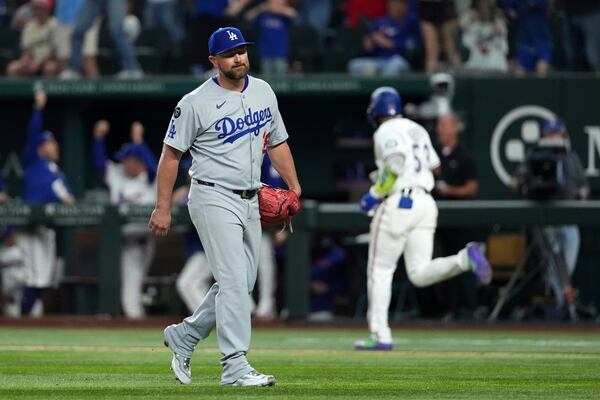 Los Angeles Dodgers pitcher Kirby Yates, foreground, walks off the field after giving up a walkoff two-run home run to Texas Rangers' Adolis García, back right, that also scored Josh Smith during the ninth inning of a baseball game Saturday, April 19, 2025, in Arlington, Texas. (AP Photo/Jeffrey McWhorter)