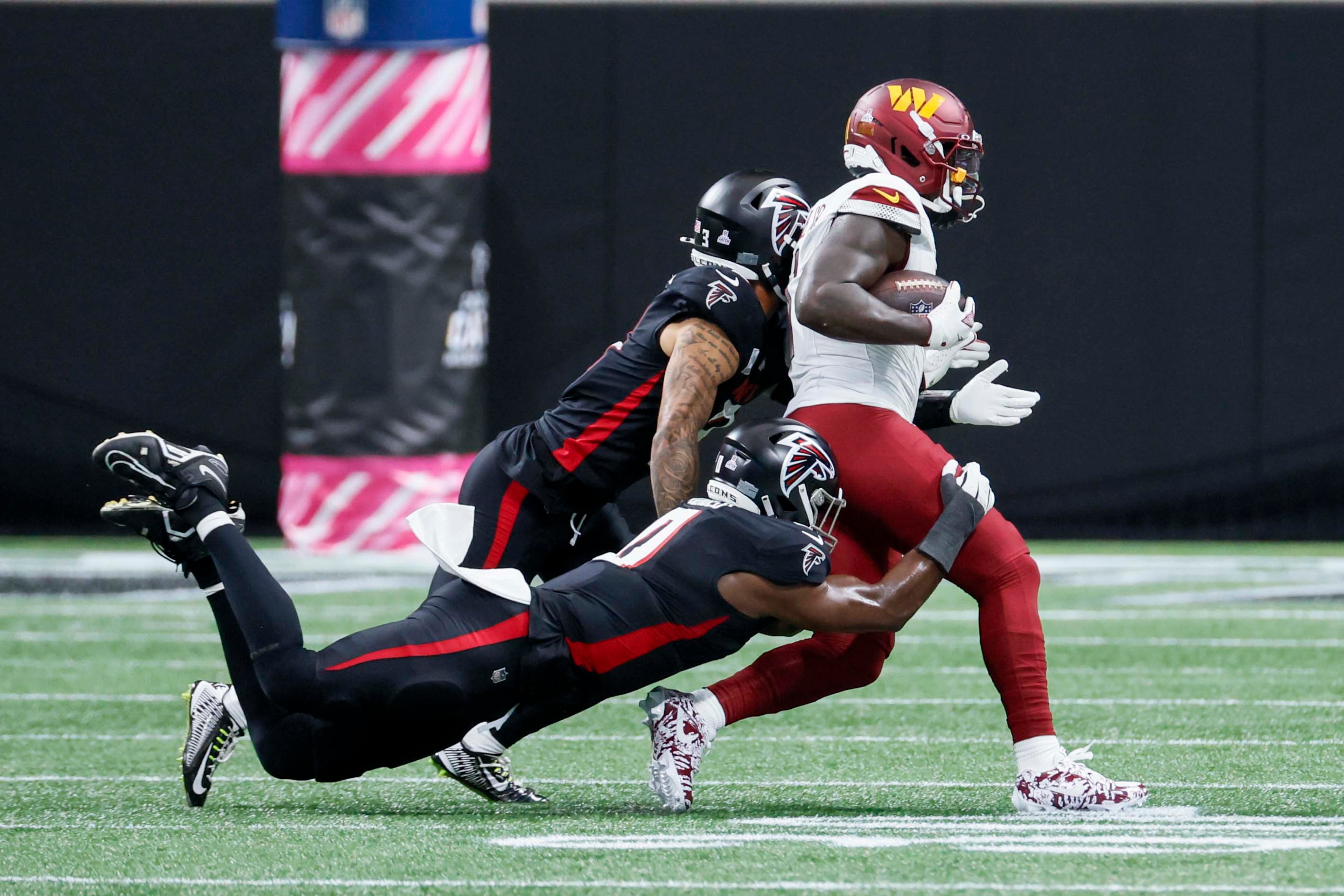 Falcons linebacker Divine Deablo (bottom left) tackles Washington Commanders wide receiver Deebo Samuel Sr. during the first half of an NFL football game against the Washington Commanders at Mercedes-Benz Stadium in Atlanta on Sunday, September 28, 2025. (Miguel Martinez/AJC)