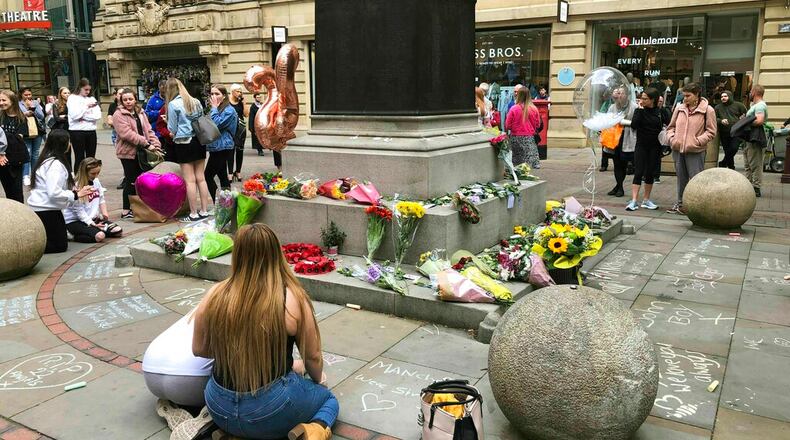 People lay flowers in St. Ann's Square in Manchester, England, Wednesday, May 22, 2019 to remember the second anniversary of the Manchester Arena terror attack where twenty-two people were murdered when suicide bomber Salman Abedi detonated a device in the foyer at the end of Ariana Grande show. (Kim Pilling/PA via AP)