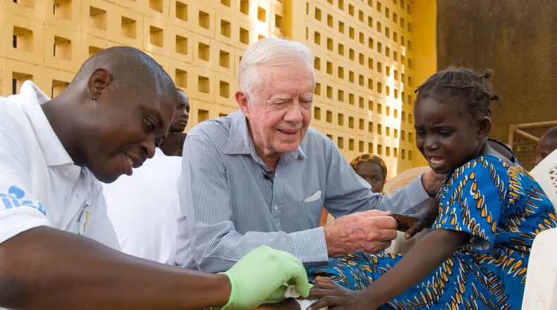 Jimmy Carter consoles a young patient having a worm removed from her body in Savelugu, Ghana, in February 2007. The Carter Center leads the international campaign to eradicate Guinea worm disease. (The Carter Center)