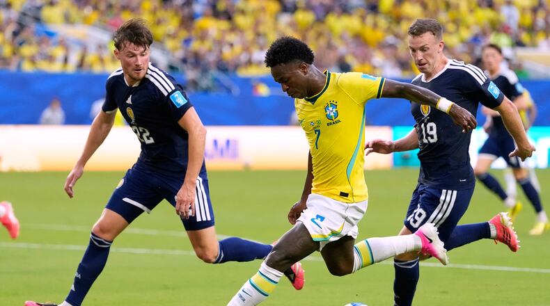 Brazil's Vinicius Junior (7) battles for the ball with with Scotland's Nathan Patterson (22) and Lewis Ferguson (19) during the World Cup Group C soccer match between Scotland and Brazil in Miami Gardens, Fla., Wednesday, June 24, 2026. (AP Photo/Rebecca Blackwell)