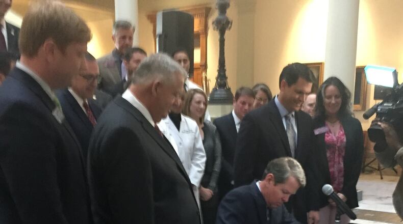 Gov. Brian Kemp, flanked by House Speaker David Ralston and Lt. Gov. Geoff Duncan at the state Capitol, signs Senate Bill 106, the Medicaid and Affordable Care Act waiver bill on March 27. (PHOTO by Ariel Hart / ahart@ajc.com)