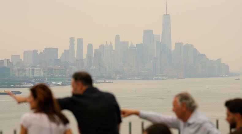 People look over the New York City skyline shrouded in smoke in Weehawken, N.J., Thursday, July 16, 2026. (AP Photo/Seth Wenig)