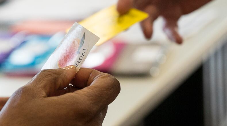 03/19/2019 -- Lilburn, Georgia -- A Gwinnett County poll worker hands a voter a sticker after casting their ballot during the Gwinnett County MARTA referendum special election at the Mountain Park Aquatic Center and Activity Building in Lilburn, Tuesday, March 19, 2019. (ALYSSA POINTER/ALYSSA.POINTER@AJC.COM)