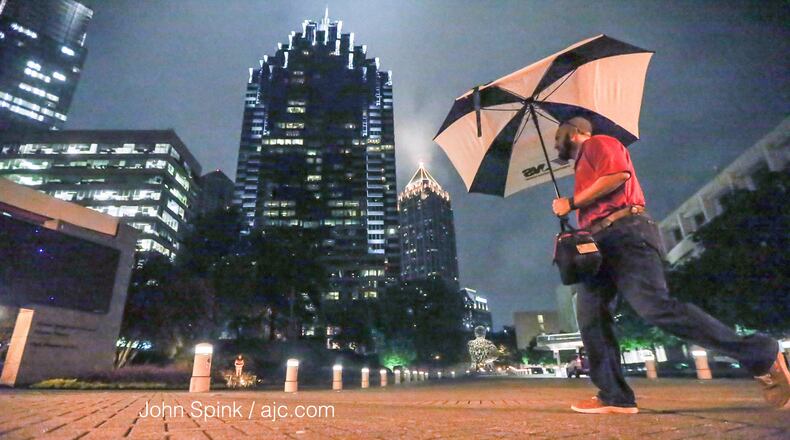 Justin Pinyan had his umbrella ready as he walked by the Woodruff Arts Center in Midtown on his way to work Friday morning. JOHN SPINK / JSPINK@AJC.COM