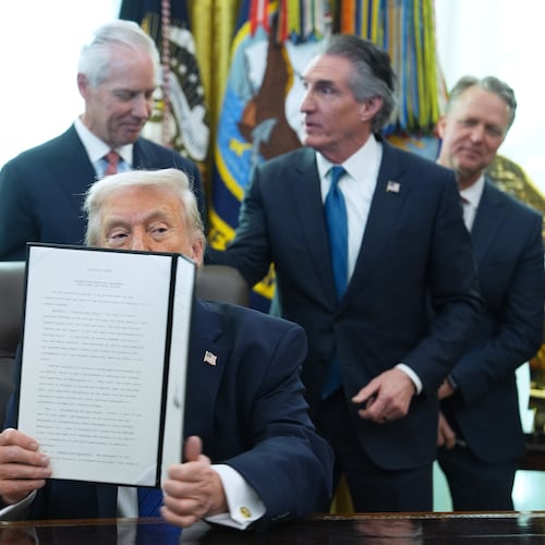 President Donald Trump holds an executive order he signed in the Oval Office of the White House, Friday, Jan. 30, 2026, in Washington. (AP Photo/Evan Vucci)