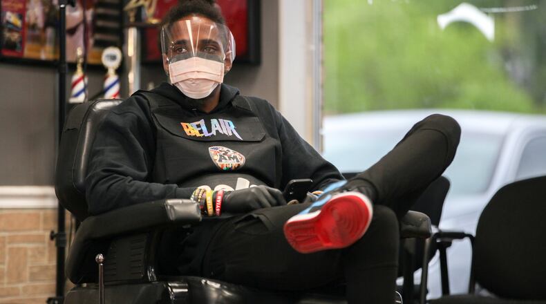 Barber Carlton O’Shea listens Wednesday in Marietta as Blessed Up Barber Shop Owner Taurean Overall, not pictured, goes over safety measures to help prevent the spread of coronavirus when they open back up on Friday. Gov. Brian Kemp is allowing certain businesses to reopen. BRANDEN CAMP/SPECIAL