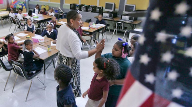 First grade teacher Marta Troutman high-fives students who lined up correctly at the DeKalb Elementary School of the Arts. The school will now be known as DeKalb Arts Academy. (AJC file photo)