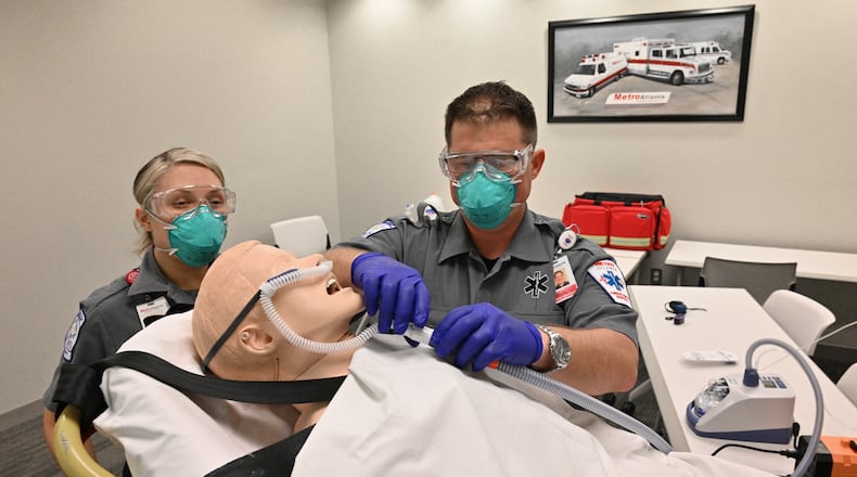 Rob Bozicevich, an EMS Academy manager, demonstrates a high-flow nasal cannula device on a patient simulator as paramedic student Devin Drinkwater watches, at the Metro Atlanta Ambulance Service in Marietta. The pandemic has changed the way emergency crews work. Now, EMS workers are adapting to the need to treat more patients with respiratory distress, etc. (Hyosub Shin / Hyosub.Shin@ajc.com)