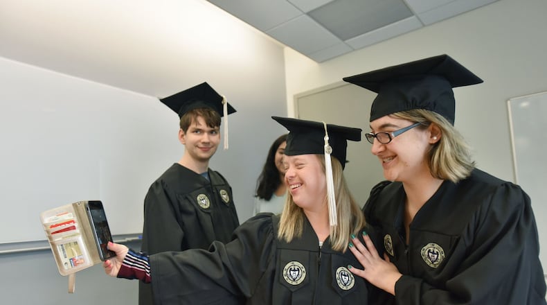 Alex Goodman and Faith Roman (right) pose for a selfie with Kurt Vogel in the background as they try on their caps and gowns ahead of their graduation from the EXCEL program for students with intellectual disabilities at Georgia Tech’s Scheller College of Business.