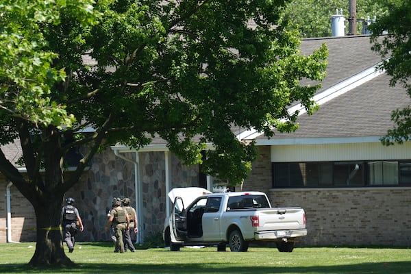 Police walk by an idle vehicle near CrossPointe Community Church in Wayne, Mich., Sunday, June 23, 2025. (AP Photo/Paul Sancya)