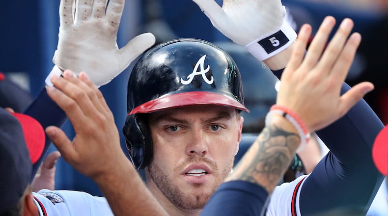 Braves first baseman Freddie Freeman gets double high fives in the dugout.