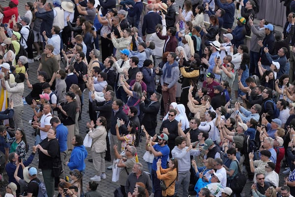 People watch as the black smoke billows from the chimney of the Sistine Chapel where 133 cardinals are gathering on the second day of the conclave to elect a successor to late Pope Francis, at the Vatican, Thursday, May 8, 2025(AP Photo/Markus Schreiber)