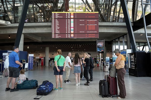 Passengers look a departures information board at Saint-Exupery airport, near Lyon, as French air traffic controllers launched a two-day strike to demand better working conditions, Friday, July 4, 2025. (AP Photo/Laurent Cipriani)