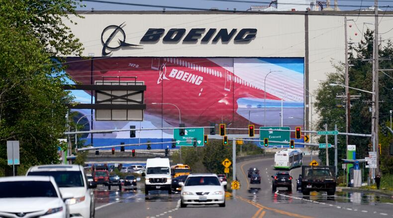 FILE - Traffic drives in view of a Boeing Co. production plant, where images of jets decorate the hangar doors on April 23, 2021, in Everett, Wash. (AP Photo/Elaine Thompson, File)