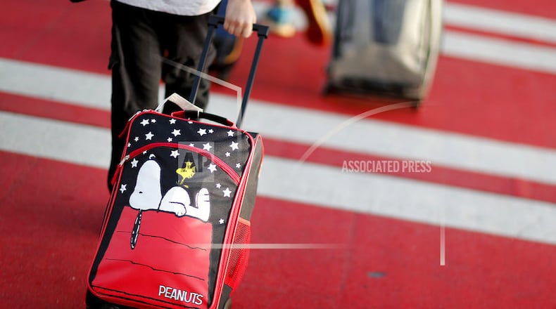 FILE - In this Nov. 22, 2017, file photo, a child pulls a suitcase along a crosswalk upon arriving at Hartsfield-Jackson Atlanta International Airport ahead of the Thanksgiving holiday in Atlanta. Parents may be feeling pressure to pay more money to sit with their young children on crowded planes despite a push by Congress to make airlines let families sit together at no extra cost. A consumer group has protested to Transportation Secretary Elaine Chao, asking her to begin writing regulations over the airlinesâ family-seating policies. (AP Photo/David Goldman, File)