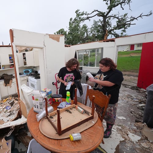 Christopher Hester, left center, talks to friend Brianna Corter, as he salvages belongings from his storm-damaged home in Mineral Wells, Texas, Wednesday, April 29, 2026. (AP Photo/Julio Cortez)