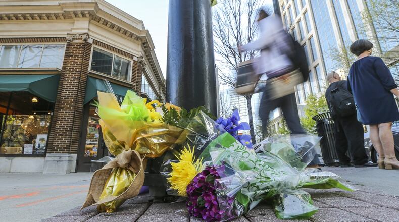 Tuesday, April 4, 2017: Neighbors, community members and well-wishers place flowers on the corner of Peachtree Street and Peachtree Place in Midtown Atlanta, where Trinh Huynh, 40, was shot to death in the crosswalk Monday. JOHN SPINK /JSPINK@AJC.COM
