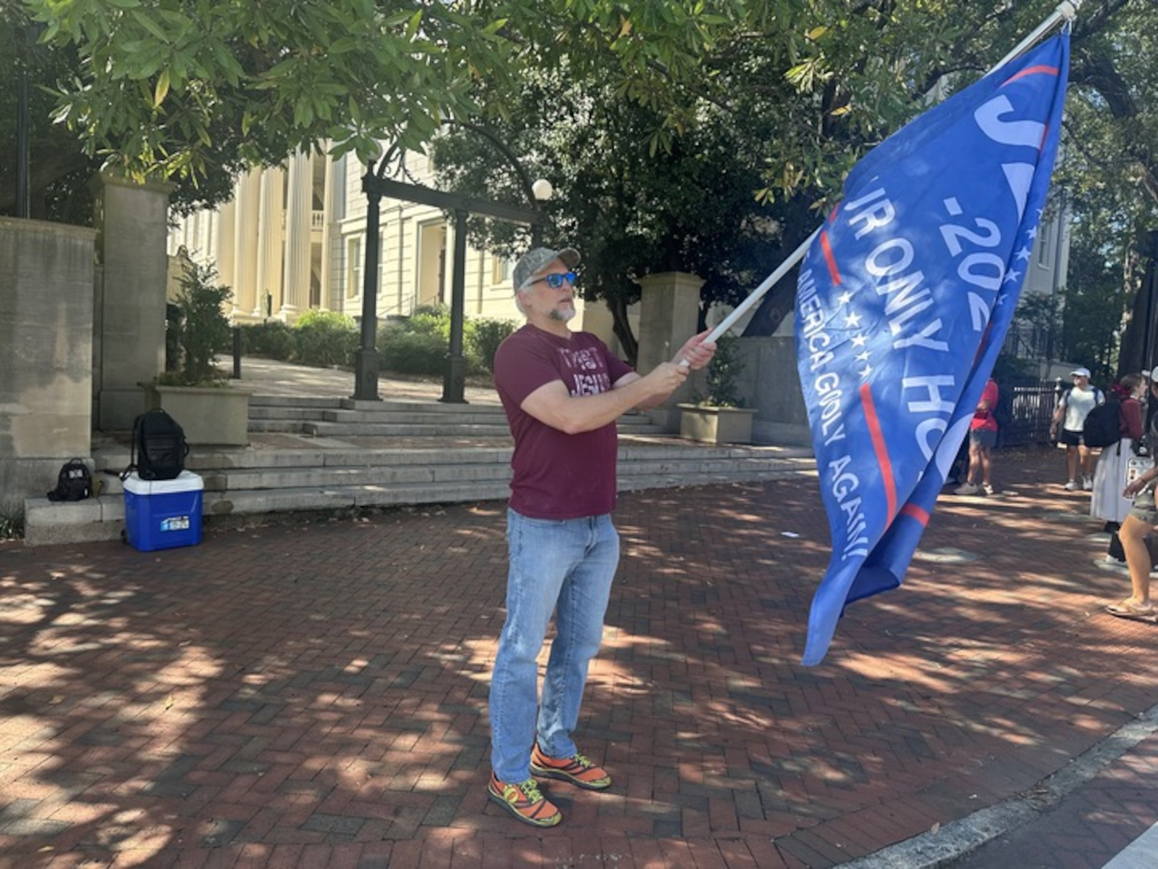 The shooting death of Charlie Kirk compelled Richard Suplita to come to The Arch on the University of Georgia campus in Athens on Thursday, Sept. 11, 2025. Suplita waved flags with Christian messages and spoke about his views to people walking toward campus and downtown. (Fletcher Page/AJC)