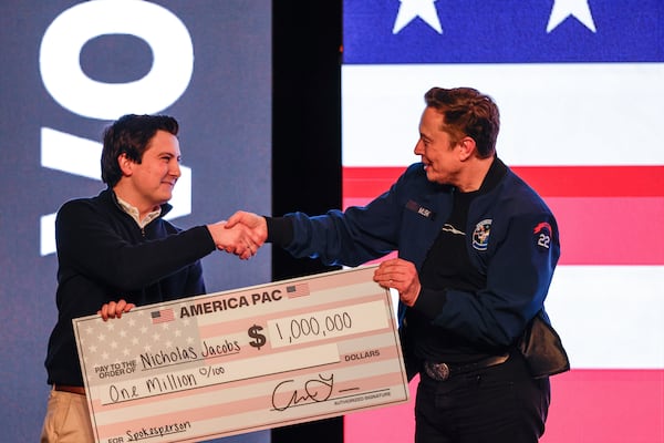 FILE - Elon Musk presents a check for $1 million dollars to a man during a town hall March 30, 2025, in Green Bay, Wis. (AP Photo/Jeffrey Phelps, File)