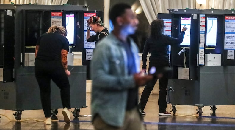 Poll workers (left to right) Alexandra Almeter, Gamble Everett, Erik Coleman and Sarah Zaslaw prepare voting machines before the polls opened on Tuesday, Dec. 6, 2022 at Park Tavern in Atlanta. (John Spink / John.Spink@ajc.com)
