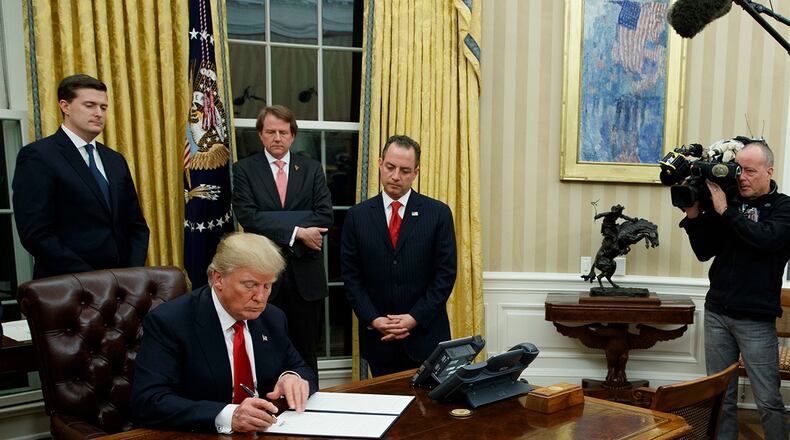 President Donald Trump signs his first executive order in the Oval Office of the White House, Friday, Jan. 20, 2017, in Washington. (AP Photo/Evan Vucci)