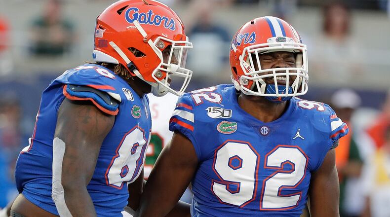 Florida defensive linemen Adam Shuler, left, and Jabari Zuniga celebrate after sacking Miami quarterback Jarren Williams on Saturday, Aug. 24, 2019, in Orlando, Fla. (AP Photo/John Raoux)