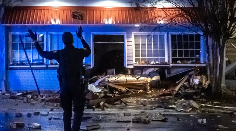 Atlanta police officers throw rocks and debris out of the road along Ponce de Leon Avenue after the roof of Mary Mac’s Tea Room partially collapsed overnight Wednesday.
