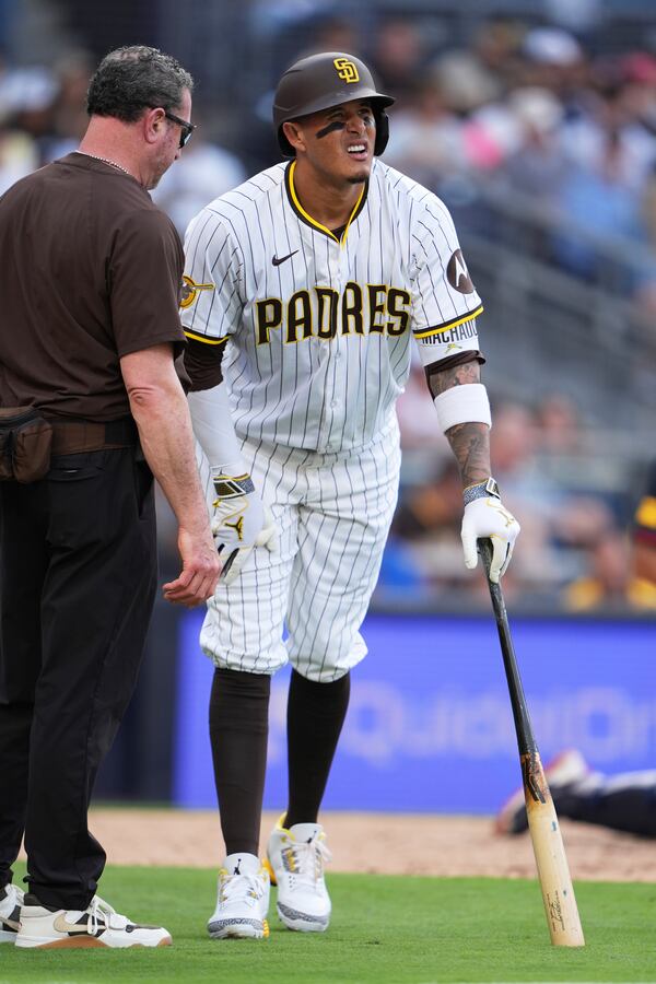 San Diego Padres' Manny Machado holds his leg after an injury while batting during the fourth inning of a baseball game against the Atlanta Braves Saturday, March 29, 2025, in San Diego. (AP Photo/Gregory Bull)