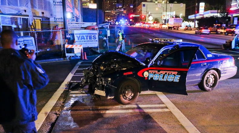 An Atlanta Police Department crime scene technician takes pictures (left) after an accident involving an Atlanta police officer and another car at 10th and Williams Streets in downtown Atlanta on Sept. 25, 2012.
