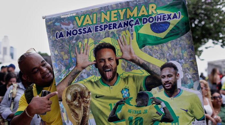 A fan poses with a poster of Brazilian soccer player Neymar, reading in Portuguese "Go Neymar, our hope for a sixth World Cup title" before Brazil's 2026 World Cup squad is announced, in Rio de Janeiro, Monday, May 18, 2026. (AP Photo/Bruna Prado)